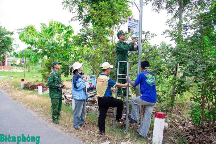 Cán bộ, chiến sĩ Đồn Biên phòng Lạc Quới cùng đoàn viên, thanh niên lắp đặt pano tuyên truyền phòng, chống mua bán người trên tuyến đường giao thông nông thôn xã Ba Chúc. Ảnh: Huy Hoàng