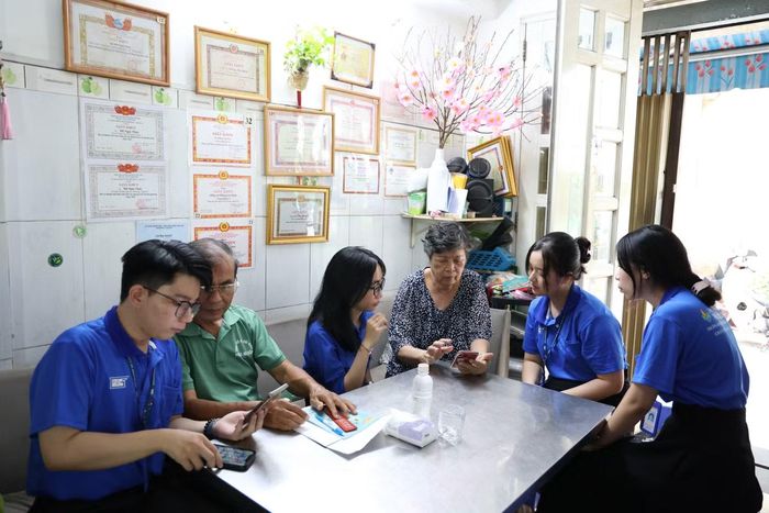 Sinh viên Sư phạm hỗ trợ các cô chú sử dụng app Sổ tay đảng viên điện tử. Ảnh: Ngô Tùng
