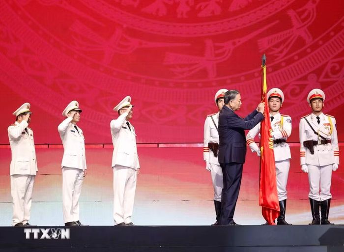 Tổng Bí thư, Chủ tịch nước Tô Lâm gắn Huân chương Sao vàng lên lá cờ truyền thống của Lực lượng An ninh nhân dân. (Ảnh: Thống Nhất/TTXVN)