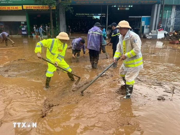 Lực lượng Cảnh sát giao thông, Công an Sơn La nạo bùn, khơi thông cống rãnh do mưa lớn kéo dài xảy ra tại xã Mường La. (Ảnh: TTXVN phát)