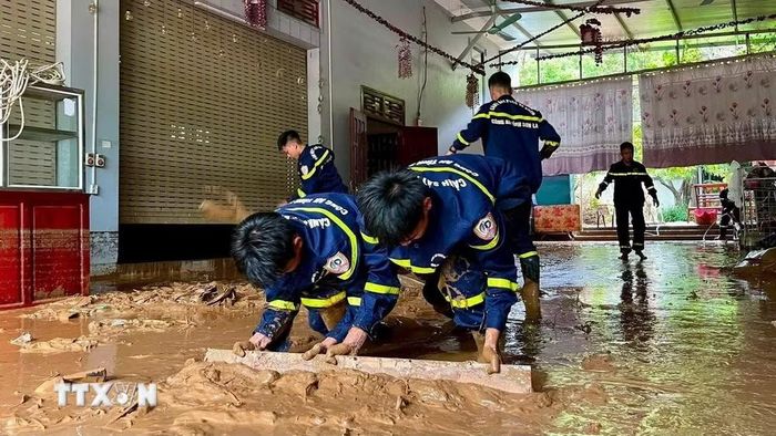 Lực lượng Cảnh sát phòng cháy chữa cháy và cứu nạn cứu hộ, Công an tỉnh Sơn La hỗ trợ người dân xã Mường La gạt bùn đất do mưa lớn trôi vào nhà. (Ảnh: TTXVN phát)