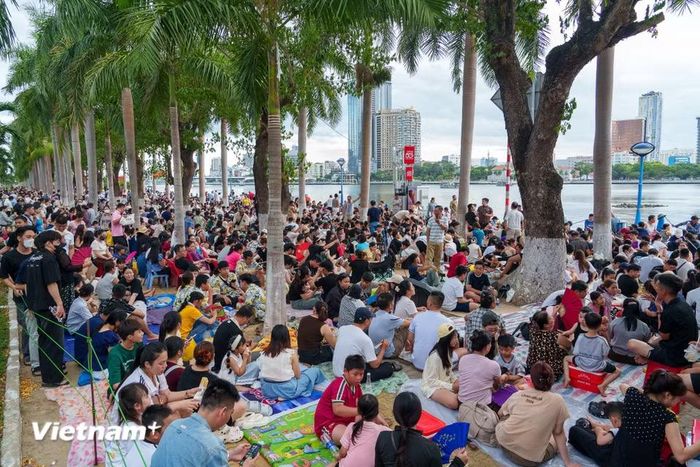 Từ đầu giờ chiều 11/7, hàng vạn người dân và du khách đã trải thảm, ngồi kín vỉa hè dọc bờ sông Hàn để chờ đón đêm chung kết Lễ hội pháo hoa Đà Nẵng (DIFF) 2026. (Ảnh: Thanh Phong/Vietnam+)