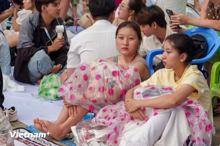 Bất chấp thời tiết không thuận lợi, nhiều khán giả trùm kín áo mưa nilon, kiên nhẫn bám trụ giữ chỗ. (Ảnh: Thanh Phong/Vietnam+)