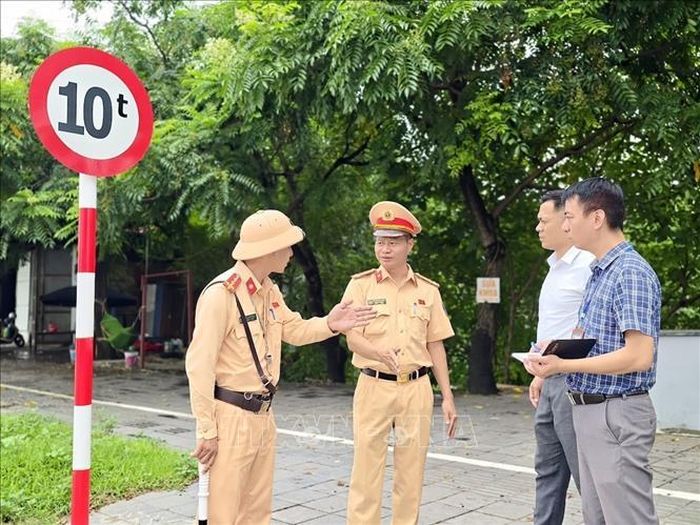 Cán bộ Đội Cảnh sát giao thông đường bộ số 15 (Phòng Cảnh sát giao thông Hà Nội) phối hợp với chính quyền địa phương kiểm tra thực tế hệ thống biển báo hạn chế trọng tải trên đường Lê Hữu Tựu (xã Phúc Thịnh) sau phản ánh của người dân. Ảnh: Trung Nguyên/TTXVN