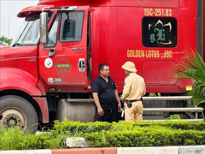 Cán bộ Đội Cảnh sát giao thông đường bộ số 15 (Phòng Cảnh sát giao thông Hà Nội) tuyên truyền, hướng dẫn lái xe chấp hành quy định về tải trọng và lộ trình lưu thông đối với phương tiện ra, vào khu công nghiệp Nguyên Khê. Ảnh: Trung Nguyên/TTXVN