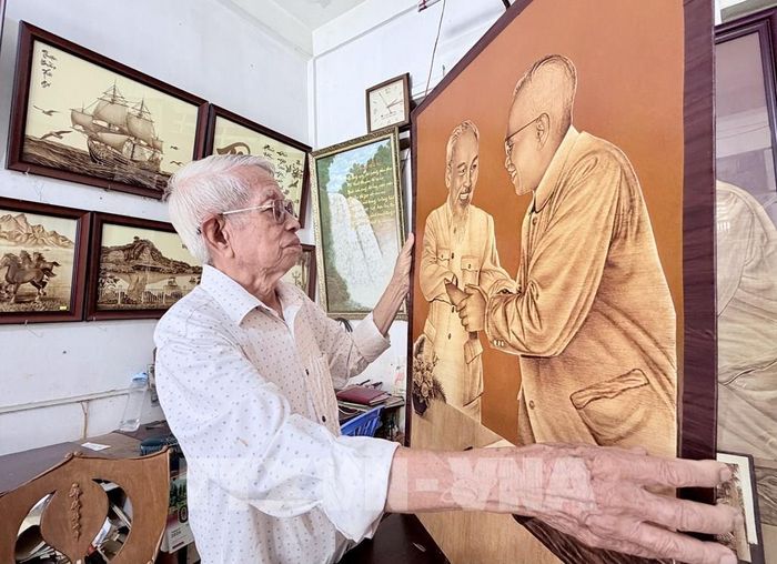 Nghệ nhân Võ Văn Tạng kiểm tra tác phẩm khắc họa chân dung Chủ tịch Hồ Chí Minh và Chủ tịch Tôn Thắng trên lá thốt nốt. Ảnh: Thanh Sang -TTXVN