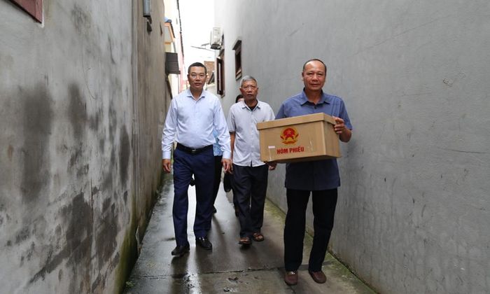 Đồng chí Nguyễn Văn Hoàn (trái), Bí thư Đảng ủy xã Yên Phong cùng thành viên Tổ lấy ý kiến thôn Phú Mẫn đưa hòm phiếu trực tiếp đến các hộ dân.