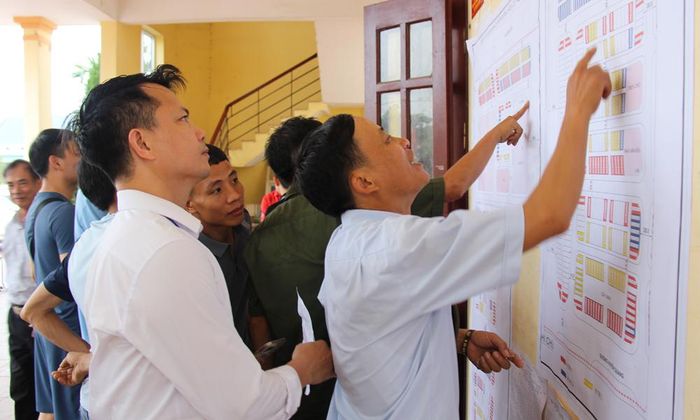 Người dân phấn khởi xác định vị trí lô đất của gia đình tại bản quy hoạch dự án tái định cư.