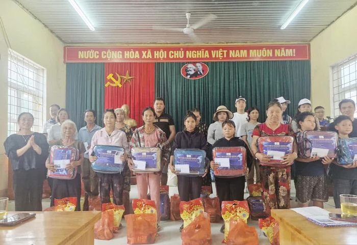 Đại diện Công ty TNHH Ait Worldwide Logistics Việt Nam và lãnh đạo xã Kim Điền trao quà cho người dân bản Hóa Lương - Ảnh: X.V