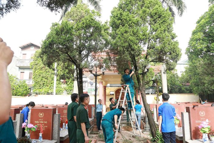 Cán bộ, hội viên các đoàn thể phát quang, vệ sinh khuôn viên nghĩa trang liệt sĩ. Ảnh: Thùy Dương