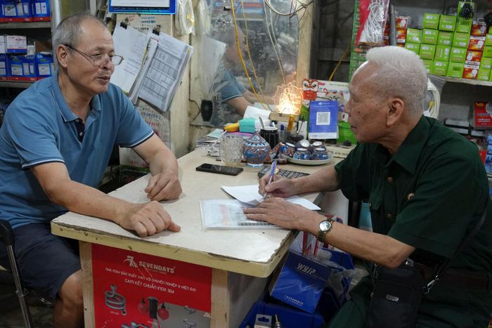 Ông Nguyễn Hồng Vuột (ngoài cùng bên trái) trao đổi với ông Trần Chiến về hiệu quả phát triển cửa hàng từ nguồn vốn vay. Ảnh: Vi Giáng