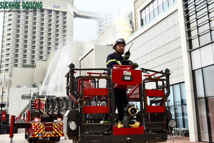 Xe thang được triển khai tiếp cận khu vực mái tầng 3 để đưa người mắc kẹt xuống mặt đất an toàn, đồng thời phối hợp phun nước khống chế đám cháy theo tình huống giả định.