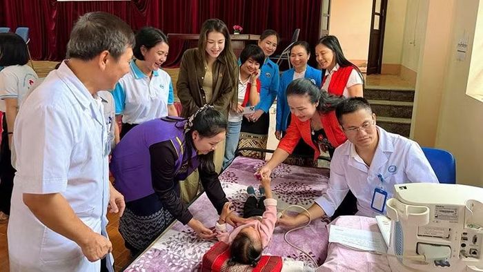 Phụ nữ cùng bác sĩ chăm sóc, khám bệnh cho trẻ em Lào.