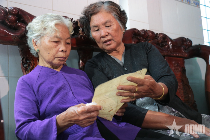  Bà Nguyễn Thị Lệ và người thân xem lại tờ giấy báo tử của liệt sĩ Huỳnh Văn Quên.
