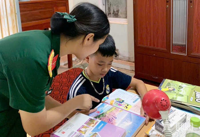 Hội viên Hội Phụ nữ Bộ CHQS tỉnh Thái Nguyên hướng dẫn con đỡ đầu Tháng Minh Quân chuẩn bị sách vở cho năm học mới.