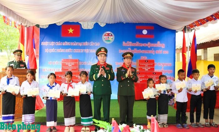 Đại tướng Phan Văn Giang và Đại tướng Khăm Liêng-Ụ Thạ Cay Sỏn trao học bổng cho học sinh Trường Tiểu học Thông Năm Mun, huyện Xay Chăm Phon, tỉnh Bô Ly Khăm Xay (Lào). Ảnh: Khánh Toàn