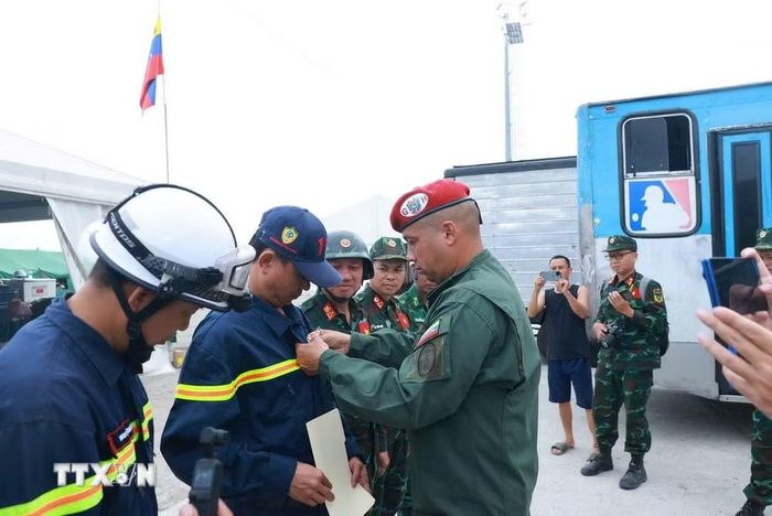 Trung tá Rául Serrano Chacón gắn huy chương "Anh hùng Venezuela" cho thành viên đoàn Việt Nam. (Ảnh: Phi Hùng/TTXVN)
