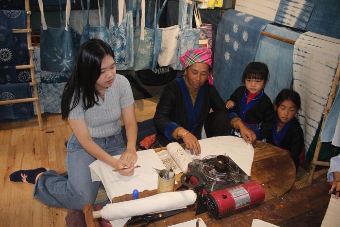 Bà Vàng Thị Mì trình diễn vẽ các hoa tiết hoa văn của người Mông lên vải trước khi nhuộm chàm. Ảnh: Chu Khôi.