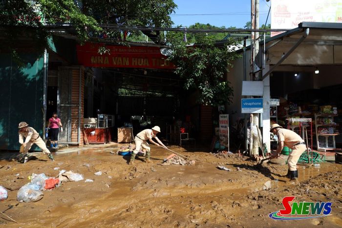 Tổ Cảnh sát giao thông khu vực Mường La hỗ trợ người dân dọn dẹp bùn đất sau mưa lũ.