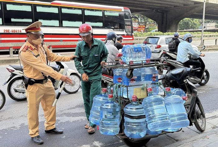 Một trường hợp xe máy chở nhiều bình nước làm che khuất biển số bị cán bộ Đội Cảnh sát giao thông số 7 yêu cầu dừng phương tiện và kiểm tra. Ảnh: Trung Nguyên - TTXVN