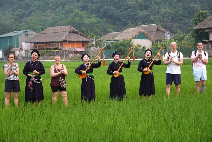 Du khách quốc tế trải nghiệm không gian văn hóa hát then, đàn tính của đồng bào Tày tại thôn Tha, phường Hà Giang 1, tỉnh Tuyên Quang. Ảnh: Minh Tâm - TTXVN