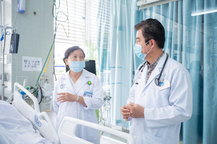  BS Lý Ích Trung (phải) trao đổi với PGS Phạm Thị Ngọc Thảo về tình hình người bệnh. 