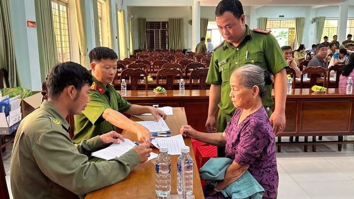 Công an xã Tân Thạnh hỗ trợ thân nhân liệt sĩ kiểm tra xác nhận thông tin.