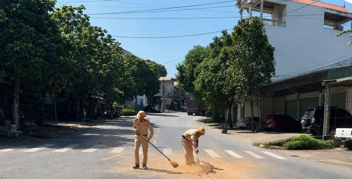 Cán bộ, chiến sĩ cảnh sát giao thông thu dọn đất rơi vãi, bảo đảm giao thông an toàn, thông suốt.