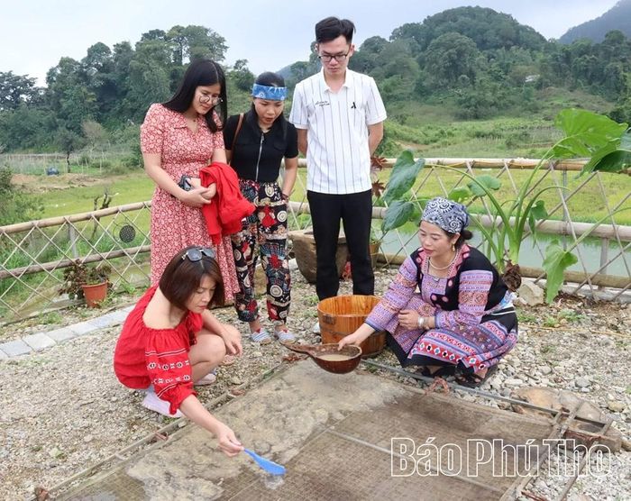 Du khách trải nghiệm công đoạn dàn đều bột giấy lên khung sắt.
