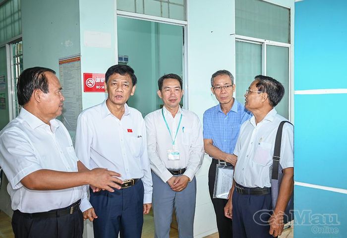 Phó Chủ tịch UBND tỉnh Cà Mau Nguyễn Minh Luân (bìa trái) trao đổi với Chủ tịch Hội đồng Dân tộc của Quốc hội Lâm Văn Mẫn (thứ hai từ trái sang) tại buổi khảo sát thực tế ở Trạm Y tế xã Khánh Lâm.