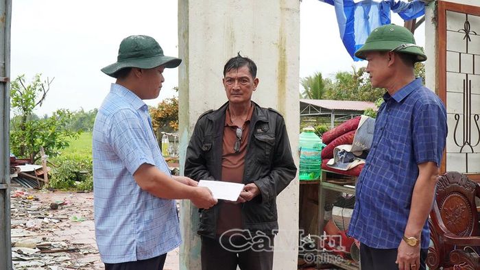 Ông Tô Hoài Phương, Giám đốc Sở Nông nghiệp và Môi trường, trao số tiền hỗ trợ cho hộ dân ở xã Khánh Bình có nhà bị tốc mái.