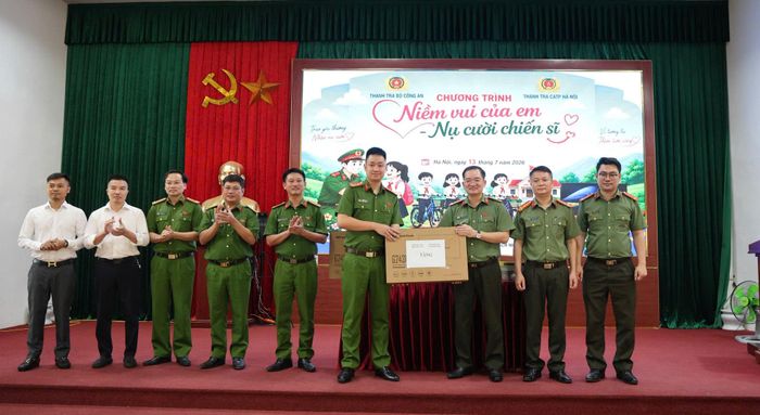 Đại tá Đoàn Đức Thắng, Chánh Thanh tra Công an thành phố Hà Nội và Đại úy Bùi Huy Bình, Trưởng Công an xã Tam Hưng trao - nhận quà tại chương trình. Ảnh: Bình Minh 