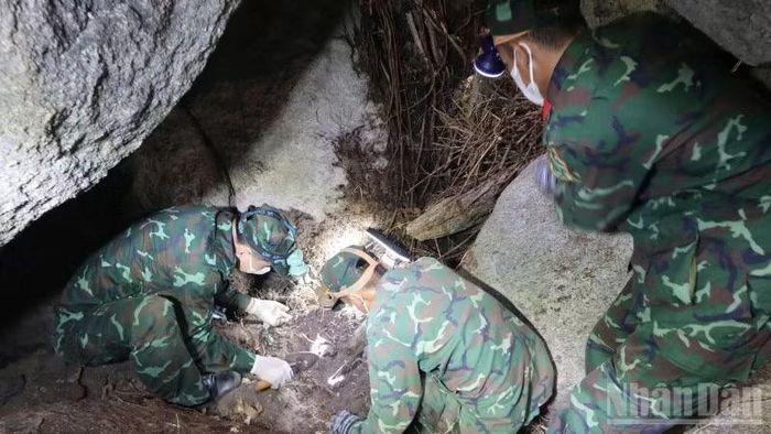 Cán bộ, chiến sĩ cẩn trọng gỡ từng phiến đá dưới hang sâu để tìm hài cốt liệt sĩ.
