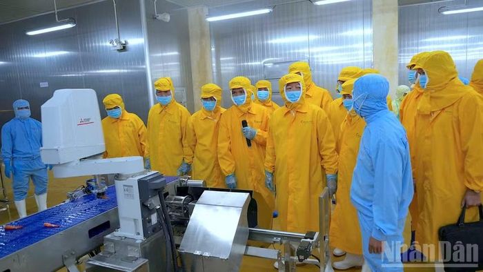 Phó Thủ tướng Chính phủ Hồ Quốc Dũng (thứ 4 từ phải qua) trò chuyện với đội ngũ kỹ thuật tại xưởng sản xuất.