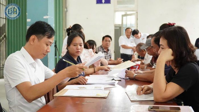 Công chức phường Đông Hòa giải quyết hồ sơ nhận tiền bồi thường của các hộ dân bị ảnh hưởng bởi dự án đường Bắc Nam 3. Ảnh: ANH TOÀN