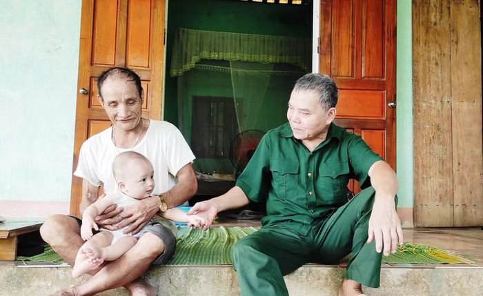 Ông Lê Văn Yêm chơi cùng cháu ở ngôi nhà trong khu đất ông khai hoang từ năm 1983. Ảnh: Thế Lượng