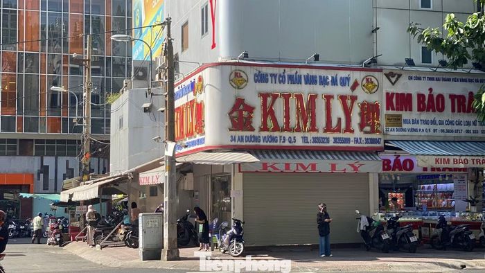 Cách tiệm vàng Ngọc Tâm hơn 100 m, cửa hàng Kim Lý trên đường An Dương Vương cũng kéo cửa cuốn mặt tiền vào khoảng sau 15h và không đón thêm khách đến giao dịch. Ảnh: Người bên trong cửa hàng lần lượt rời đi, trong khi cửa chính vẫn đóng kín.
