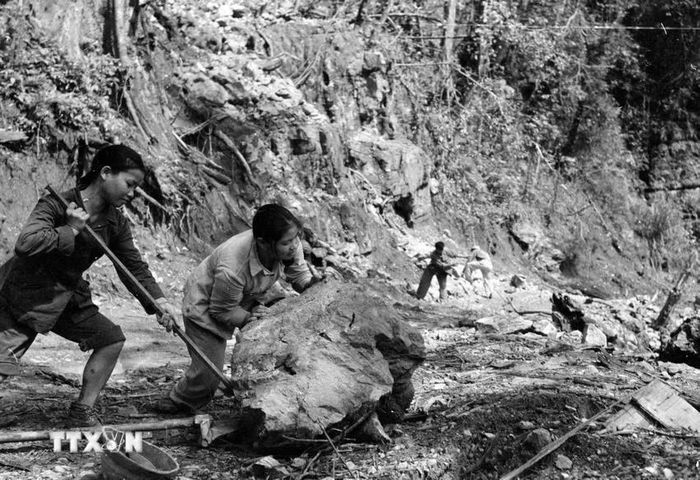 Lực lượng thanh niên xung phong đẩy đá, mở đường cho xe qua trên tuyến đường Trường Sơn. (Ảnh: Hữu Ngôi/TTXVN)