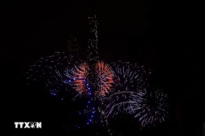 Pháo hoa kết hợp hiệu ứng ánh sáng từ drone tạo nên khung cảnh rực rỡ quanh Tháp Eiffel trong đêm 13/7 tại Paris. (Ảnh: Hữu Chiến/TTXVN)