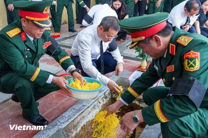 Các đại biểu rải những cánh hoa vàng xuống phần mộ, nghẹn ngào tiễn đưa đồng đội. (Ảnh: Thanh Phong/Vietnam+)