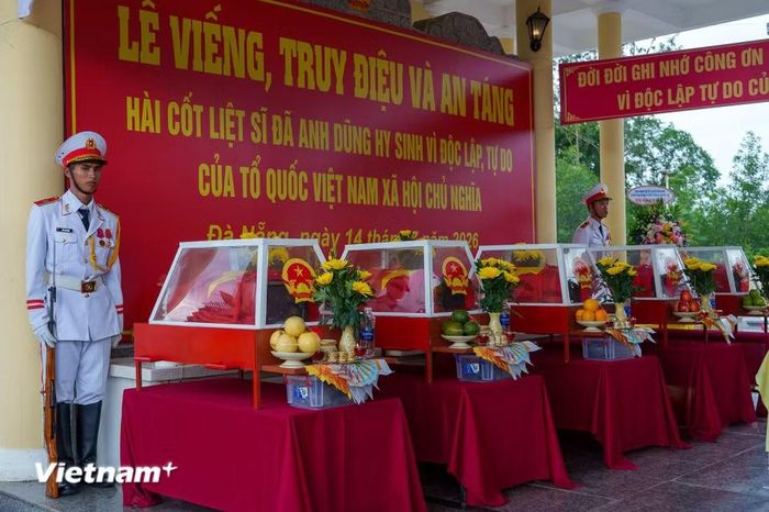 Các hài cốt liệt sĩ được phủ cờ Tổ quốc, đặt trang trọng trên bục trước giờ cử hành nghi lễ truy điệu. (Ảnh: Thanh Phong/Vietnam+)