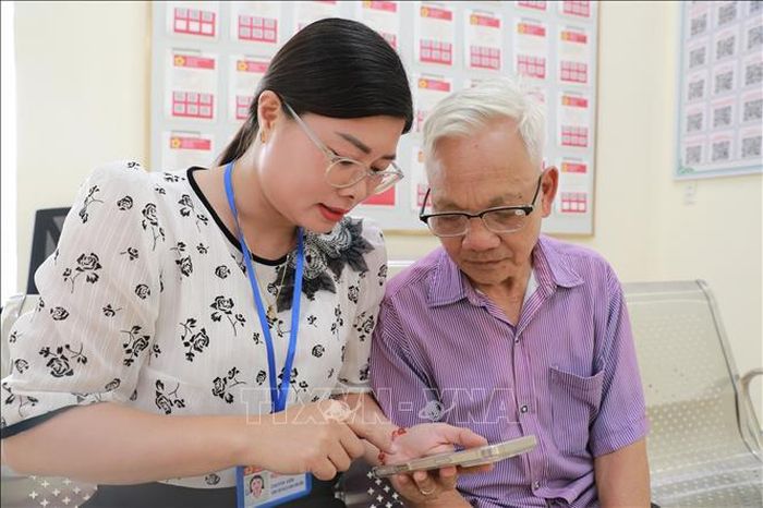 Thành viên "Tổ công nghệ số cộng đồng" xã Định Tân (tỉnh Thanh Hóa) hỗ trợ người dân cài đặt và sử dụng ứng dụng trên điện thoại thông minh. Ảnh: Khiếu Tư/TTXVN
