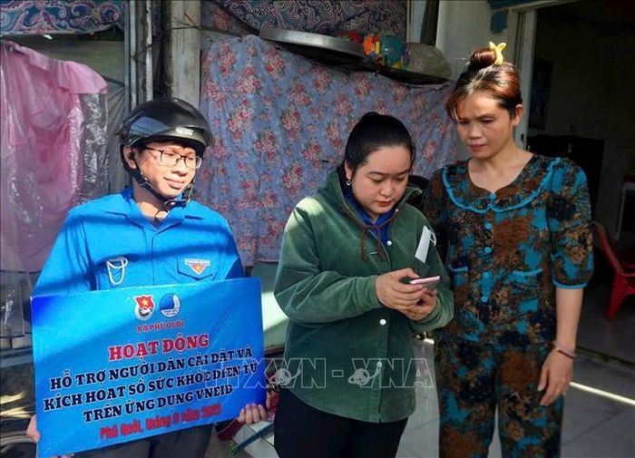Đoàn viên đến tận khu dân cư hỗ trợ người dân cài đặt và kích hoạt sổ sức khỏe điện tử trên ứng dụng VNeID tại xã Phú Quới, tỉnh Vĩnh Long. Ảnh: Lê Thúy Hằng/TTXVN