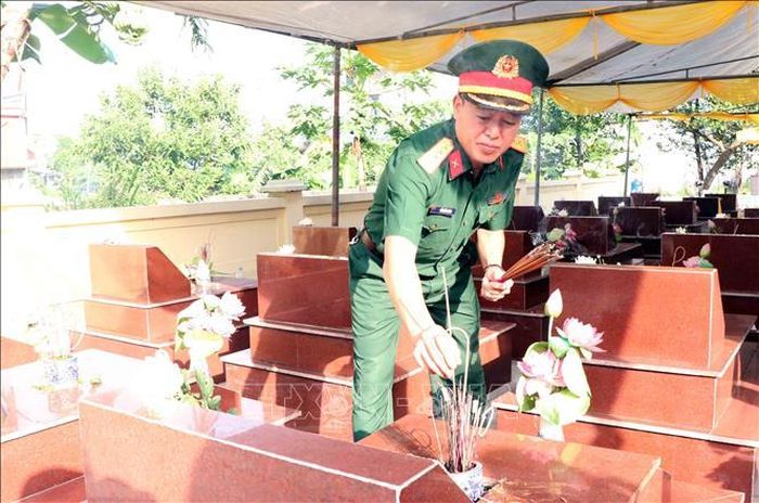 Thắp hương tại các phần mộ liệt sĩ trước khi thực hiện khai quật lấy mẫu hài cốt tại Nghĩa trang liệt sĩ xã Tân Cương. Ảnh: Trần Trang/TTXVN