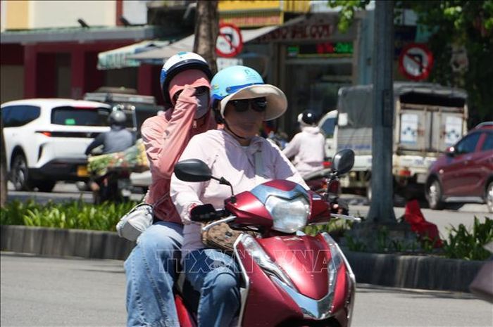 Người dân thành phố Huế mặc đồ bảo hộ chống nắng nóng gay gắt. Ảnh: Nguyên Lý/TTXVN