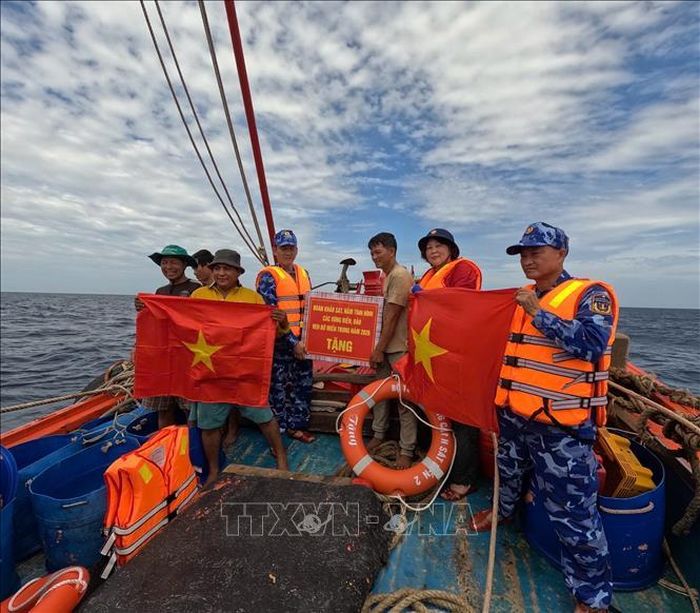 Đoàn công tác của Bộ Tư lệnh Vùng Cảnh sát biển 2 trao tặng cờ Tổ quốc, quà động viên các thuyền viên, khích lệ ngư dân yên tâm vươn khơi, bám biển. Ảnh: TTXVN phát