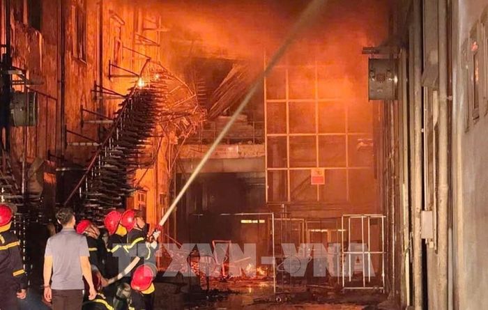 Các lực lượng chức năng đang khẩn trương tổ chức nhiều mũi tấn công vào khu vực nhà kho, đồng thời phun nước làm mát các công trình lân cận nhằm ngăn chặn cháy lan. Ảnh: Việt Hoàng - TTXVN 