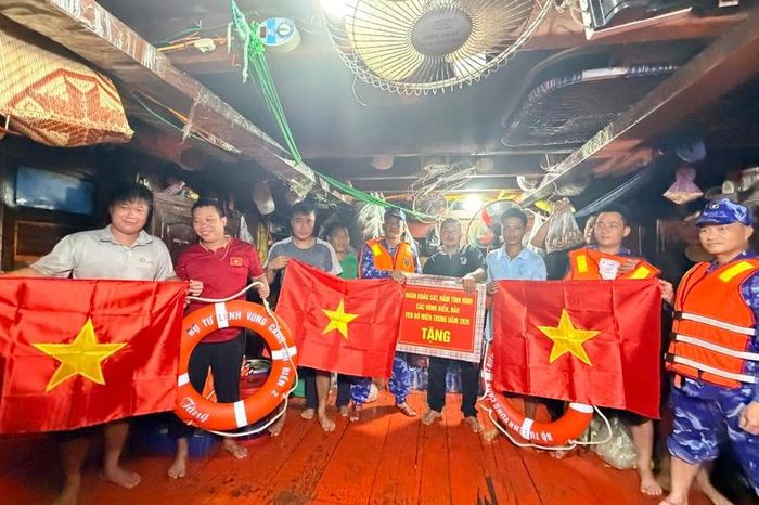 Đoàn khảo sát tặng quà, áo phao và cờ Tổ quốc cho các ngư dân đang đánh bắt trên biển. Ảnh: Diễm Phúc