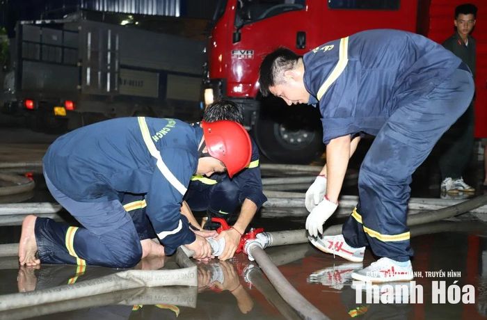 Cán bộ, chiến sĩ nối vòi tăng áp đưa nước từ bể nước chữa cháy của doanh nghiệp đến các vị trí dập lửa.