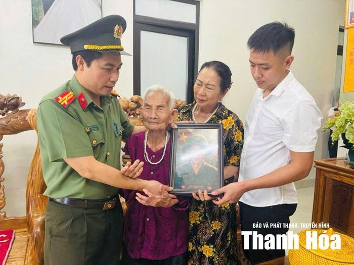 Đại diện Phòng Quản lý xuất nhập cảnh, Công an tỉnh Thanh Hóa trao ảnh liệt sĩ được phục dựng cho gia đình chính sách tại xã Sao Vàng.
